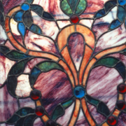 Antique Victorian stained glass window with fleur-de-lis motif in ruby, sapphire, and amber glass